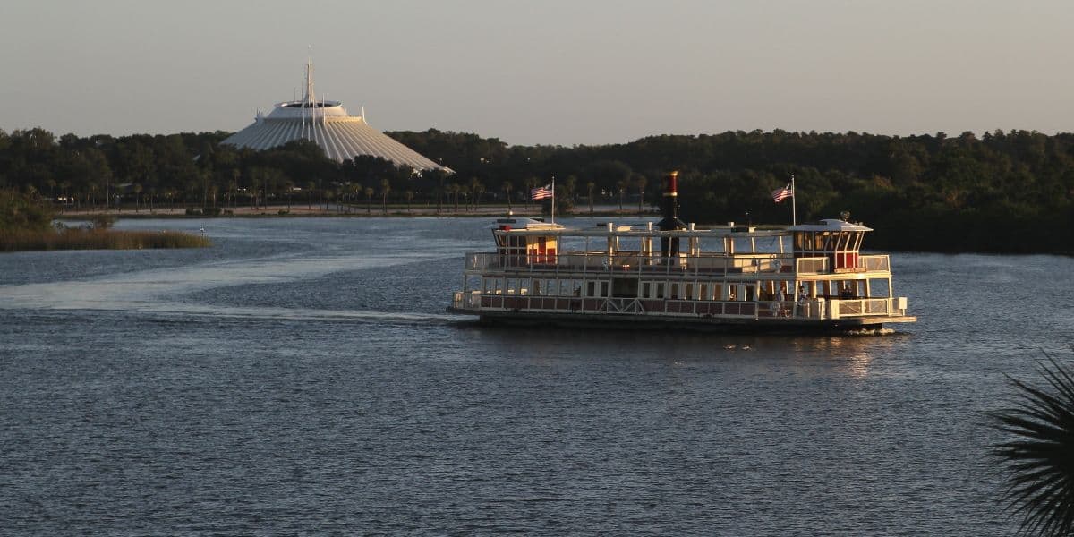 A boat sails across Seven Seas Lagoon with Space Mountain in the background