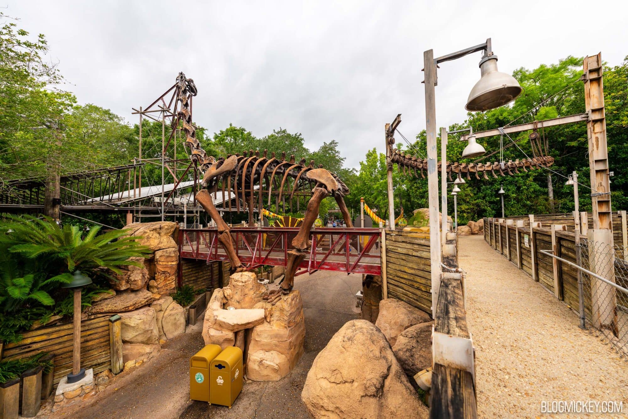 Fossil themed dinosaur skeleton in DinoLand U.S.A. section, rusty bridge, skeletal displays, and lush greenery, at Disney World's Animal Kingdom.
