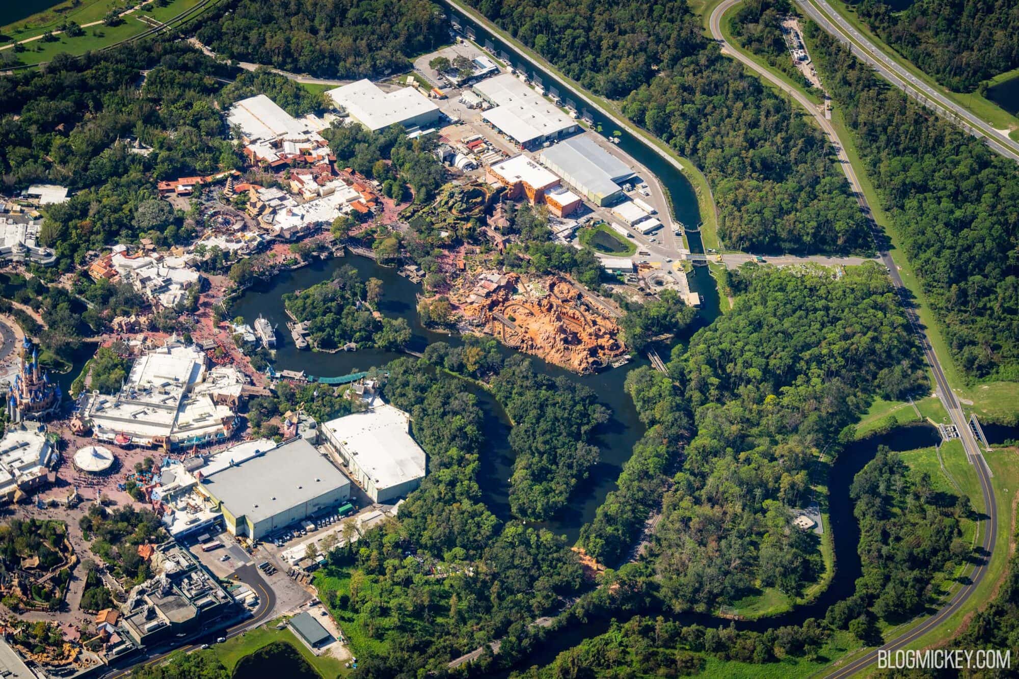 Aerial view of Magic Kingdom park at Walt Disney World featuring attractions, themed lands, Rivers of America water features, and lush greenery in the northwest corner of the park before construction began
