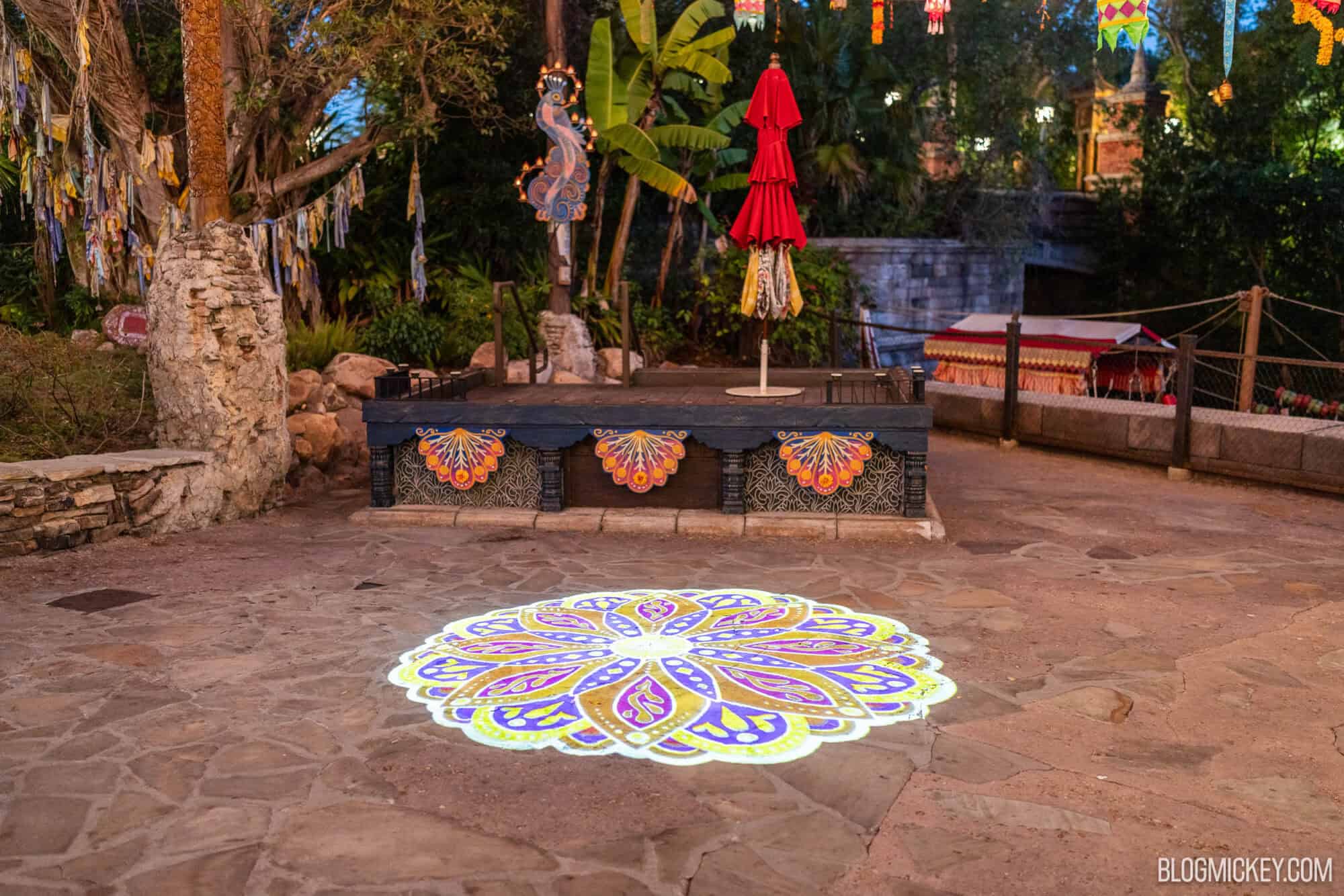 Colorful illuminated mandala projection on stone path at outdoor tropical themed area.