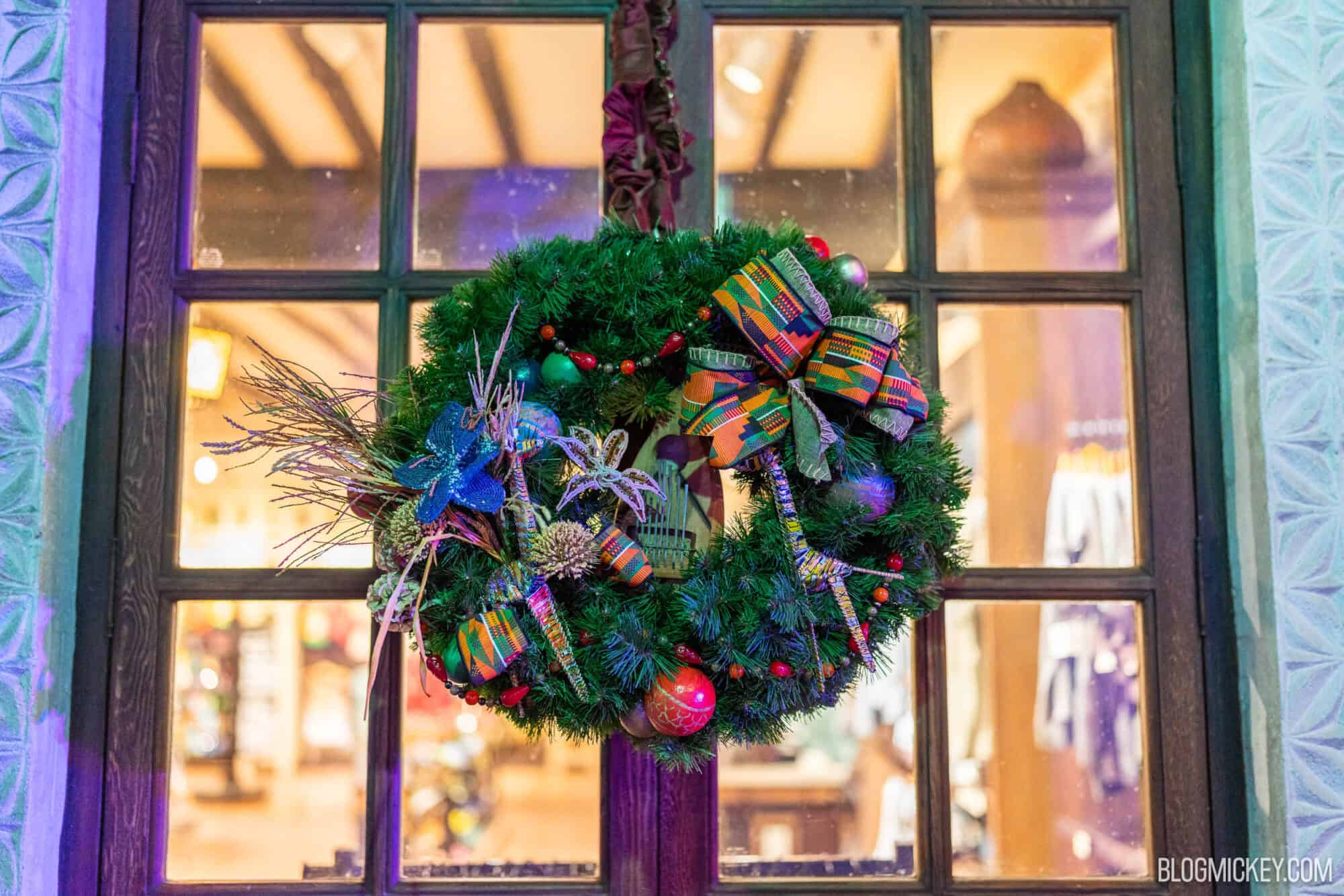 Festive holiday wreath with colorful ribbons and ornaments hanging outside.