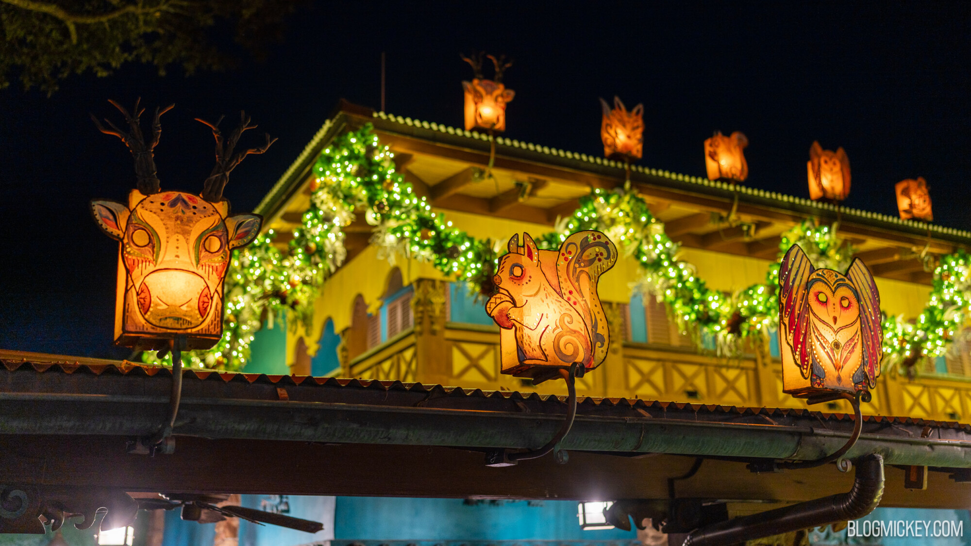 Colorful lanterns with animal designs hanging outside a decorated building at night.