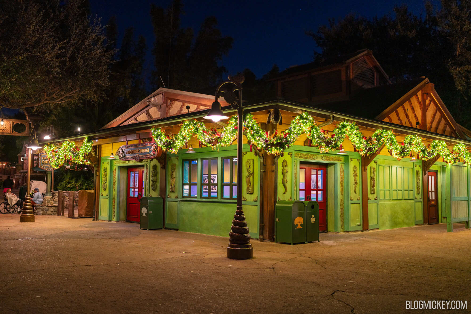 Colorful Disney-themed building decorated with festive garlands at night.