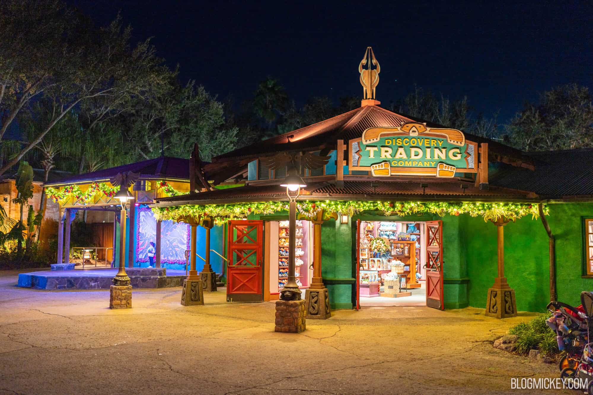Colorful discovery trading company store at night with holiday lights and decorations.