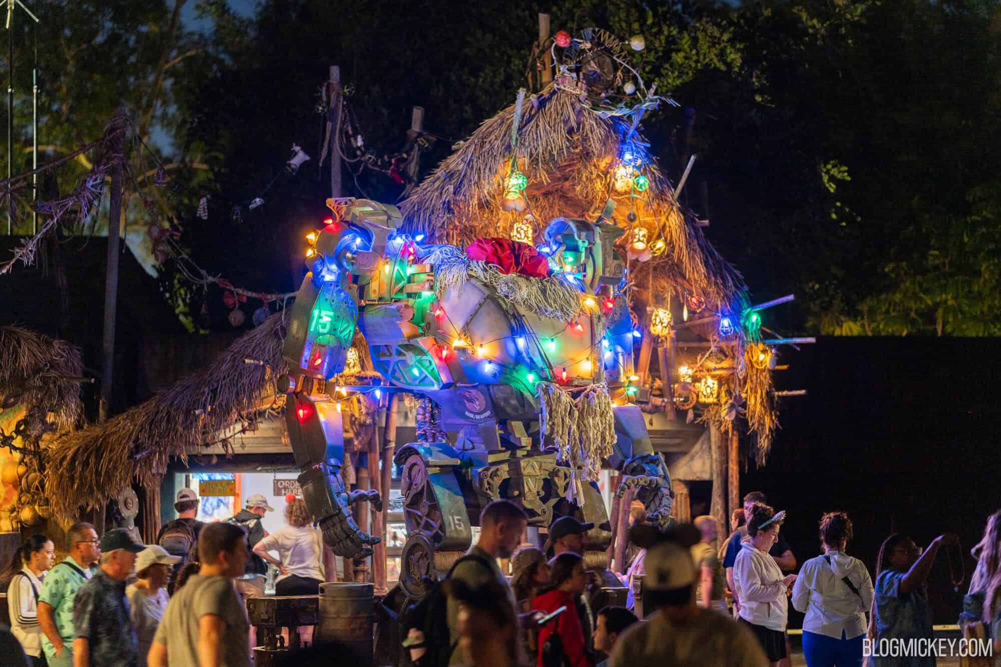Colorful illuminated robot exhibit at night with crowd of people, Disney-themed event, festive atmosphere, celebration at theme park, Tropical setting, Walt Disney World.