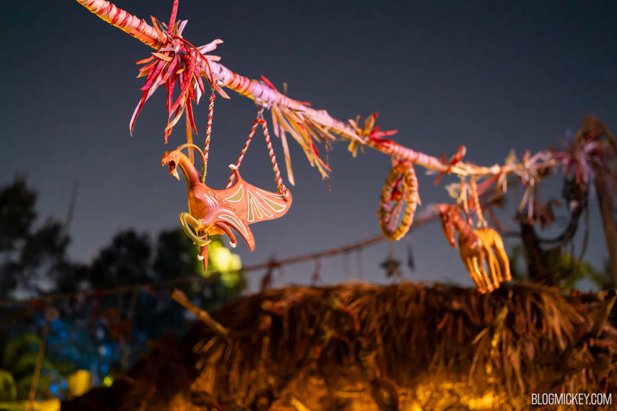 Colorful dragon-shaped decorations hanging on a decorated string at night, illuminated by soft lights.