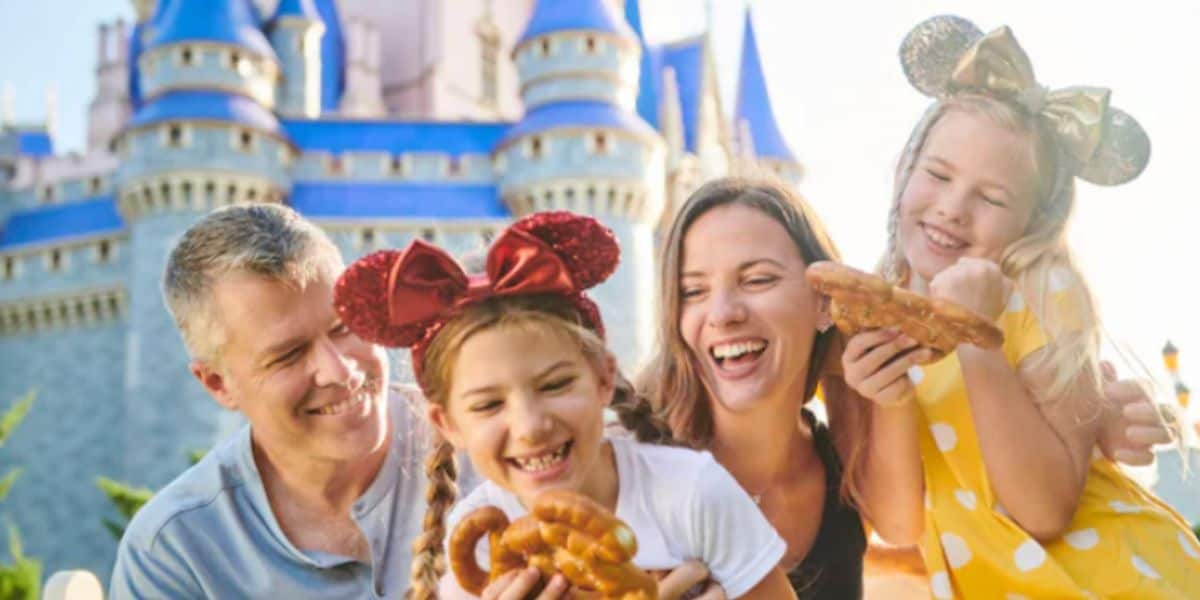 family at walt disney world's cinderella castle holding mickey pretzels