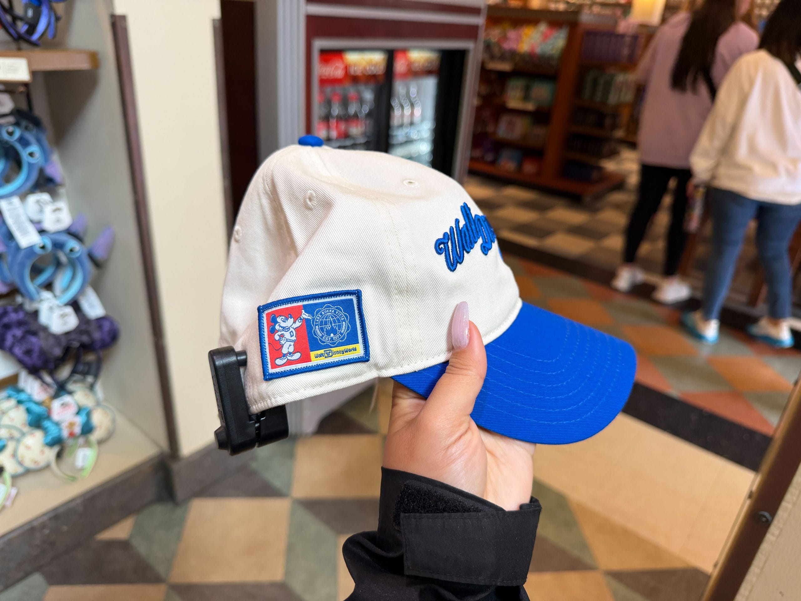 On the back of the hat, in the same royal blue, is an oval with "1971" cut out of it. The side of the hat features a patch with a vintage sports aesthetic Mickey Mouse. Beside him is a wavy circle with Cinderella Castle inside it and the words "Lake Buena Vista" and "Est. 1971." Beneath that is a tiny, vintage Disney World wordmark.