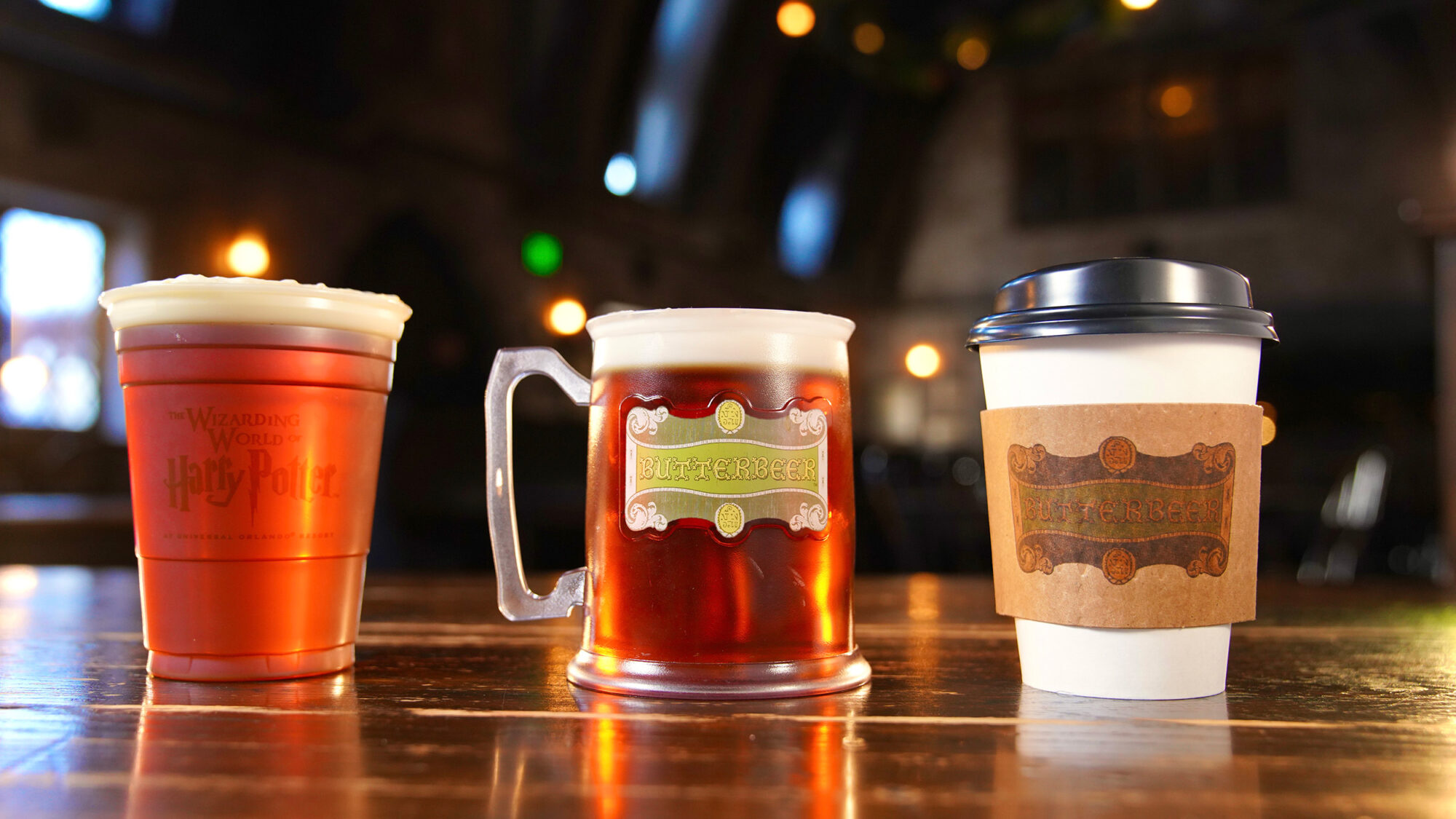 Three Butterbeer drinks on a bar counter at Universal Studios theme park.
