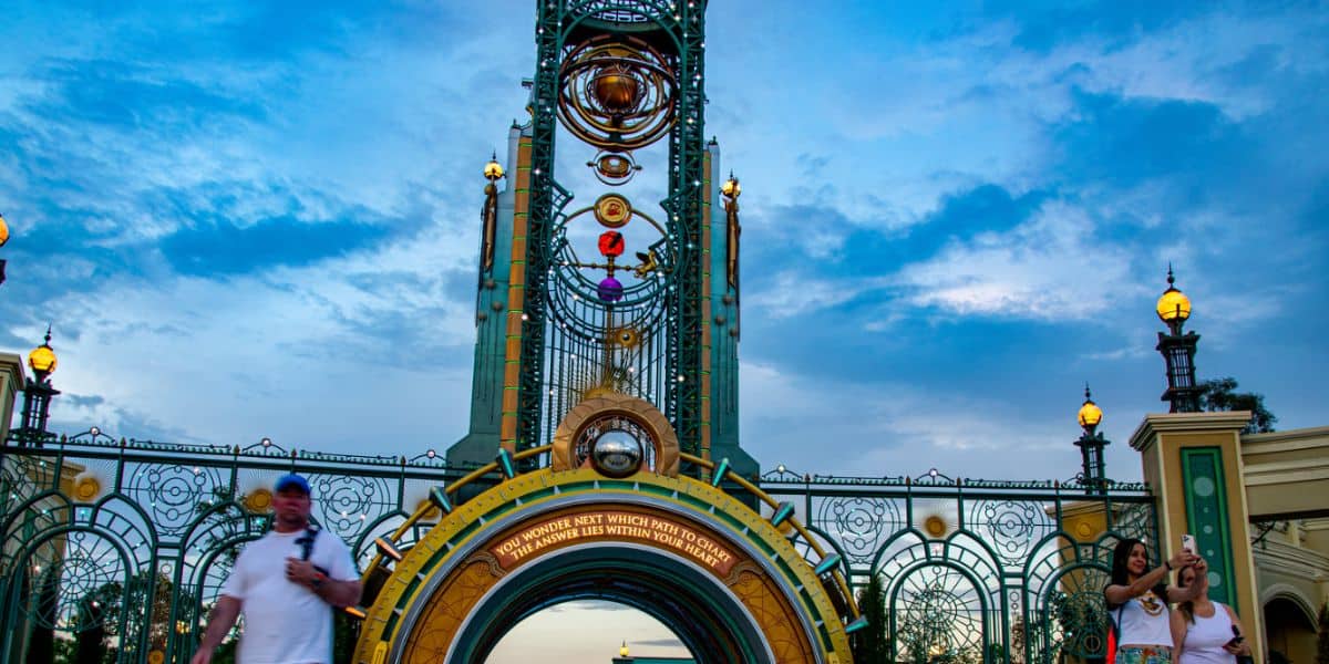 Guests snap photos by Universal Orlando’s glowing clock tower gate, buzzing with anticipation for the Epic Universe expansion.